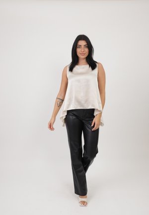 Top de satén color crema con un dobladillo fluido, combinado con pantalones de cuero negro ajustados. Diseño sencillo con una textura suave y una silueta relajada.