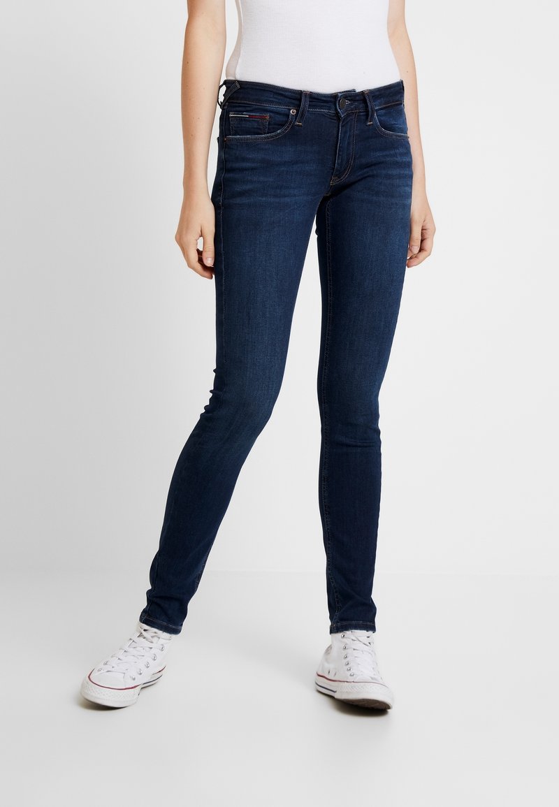 Mörkblå skinny jeans i denim, med fem fickor, bälteshällor och en lätt stretch för komfort. I kombination med vita sneakers.