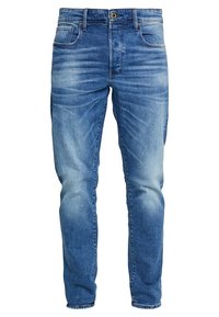 Blå denimjeans med en klassisk femfickdesign, dragkedja och en blekt tvätt med lätt slitningar på låren.