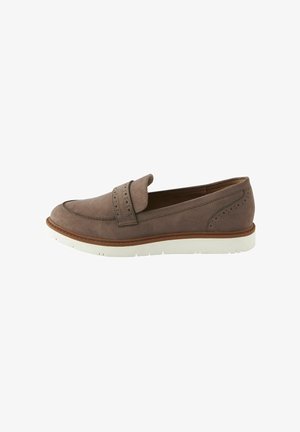 Chaussure slip-on en suede marron avec un détail de strap perforé, bout rond, semelle en caoutchouc blanc et accents de coutures le long des bords.