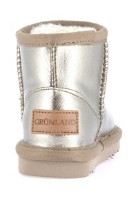 Stivale alla caviglia argentato metallizzato con fodera in pelliccia sintetica, risvolto in tessuto tan, cuciture decorative e un'etichetta in pelle tan con logo sul retro.