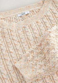 Pull en maille torsadée couleur crème avec des specks multicolores, col et poignets côtelés, et étiquette de la marque "NEXT" au niveau de l'encolure.