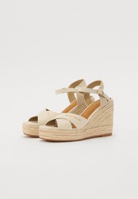 Beige kilehæle sandaler med canvasremme og en espadrille-stil flettet jute sål. Justerbar ankelrem og åben tå-design.
