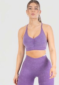 Paars sportief set bestaande uit een cropped, nauwsluitende sport-bh met plooitjes en bijpassende hoge taille legging met ribbelstructuur.