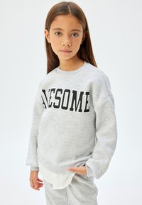 Szara bluza z napisem "AWESOME" wytłoczonym dużymi czarnymi literami na przodzie. Posiada okrągły dekolt oraz ściągacze na rękawach. Połączona z pasującymi spodniami.