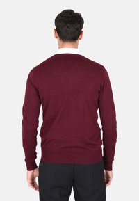 Maglione bordeaux realizzato in un morbido tessuto testurizzato; presenta maniche lunghe e un classico scollo rotondo; aderente in vita con orlo a coste.
