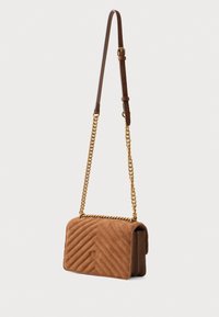 Brūna zamšīga crossbody soma ar ševronu šuvēm, zelta ķēdes siksna un regulējama ādas daļa uz baltā fona.