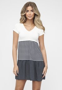 Robe à col en V avec manches courtes ; le haut est blanc uni, la moitié inférieure présente des rayures verticales bleu marine et blanches, se transformant en motif à pois.