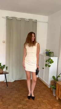 Hvit ermeløs kjole med teksturdetaljer, tilpasset fasong og mini lengde. Kombinert med svarte spisse hæler og en svart clutch.
