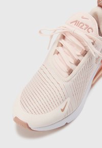 Nike Air Max 270 kengät vaaleanpunaisena ja beigeinä, joissa on teksturoitu verkkoylämateriaali, pehmustettu kaulus ja sileä valkoinen ja beige pohja.