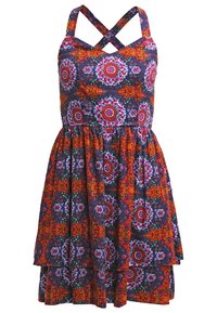 Robe à motifs floraux avec un fond bleu marine, mettant en avant des designs vifs rouges et oranges, un corsage ajusté et des bretelles croisées.