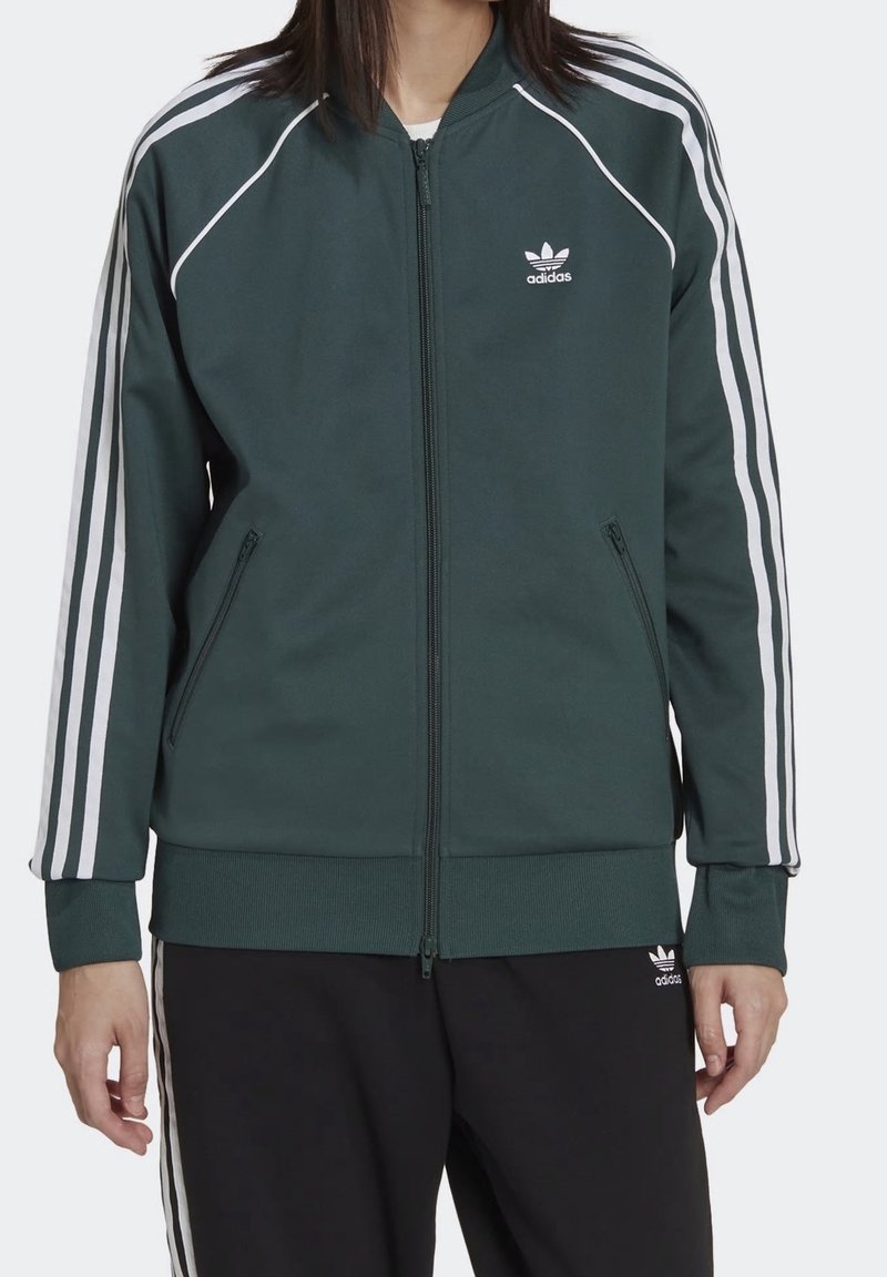 Dark green zip-up jacket with white stripe accents on sleeves, ribbed cuffs and hem, featuring the Adidas logo on the chest.