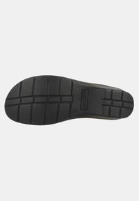 Black rubber shoe sole with deep tread lines for grip. Features logo imprint on side, showing durable construction and traction design.