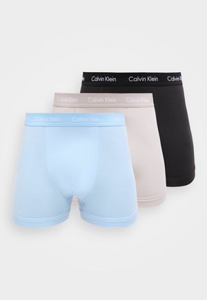 Tres pares de calzoncillos bóxer para hombre Calvin Klein en azul claro, beige y negro, cada uno con cintura con la marca.