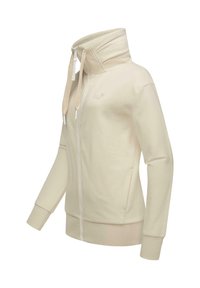 Cream-colored zip-up sweatshirt with high collar, adjustable drawstrings, and ribbed cuffs. Made from soft, textured fabric.