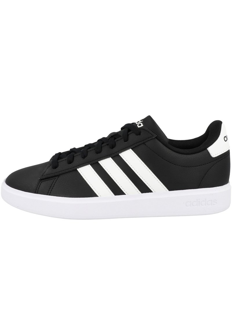 Zapatillas negras de material sintético con diseño de tres rayas blancas, cuello acolchado y suela blanca de goma. Logotipo en la lengüeta y en el talón.