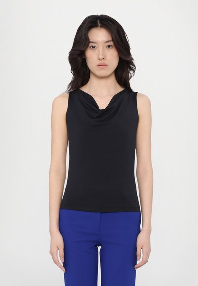 Black sleeveless top with a draped cowl neckline, made of soft fabric. Styled with blue trousers, featuring a smooth texture and fitted design.