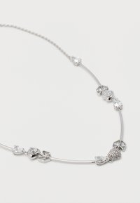 Ασημένιο κολιέ με καρδιά και γεωμετρικούς διαυγείς πολύτιμους λίθους, τοποθετημένους ομοιόμορφα σε λεπτές αλυσίδες πάνω σε λευκό φόντο.