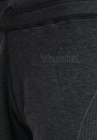 Donkergrijze joggingsbroeken van textuurstof, met een subtiele logo en een ribbelband met een trekkoord voor verstelbaarheid.