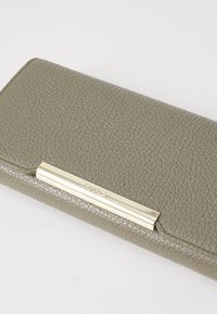 Olive green textured leather wallet with a gold-tone metal accent and embossed brand logo on the front. Compact and rectangular shape.