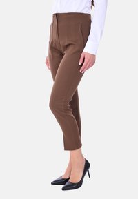 Pantaloni marroni su misura con vita alta, caratterizzati da una texture liscia e dettagli di cuciture visibili, abbinati a scarpe con tacco alto nere.