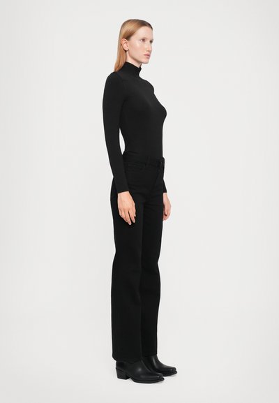 Black long-sleeve turtleneck top paired with black high-waisted jeans and black block-heel ankle boots. Simple and fitted design.