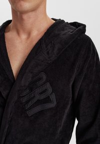 Black cotton bathrobe with a textured finish, featuring a hood and bold logo detail on the chest. Soft, comfortable fabric and loose fit.