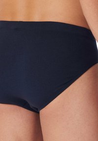 Slip da bagno da uomo in blu navy realizzati in tessuto morbido ed elastico. Presentano un taglio a vita bassa con una vita liscia e cuciture minime.