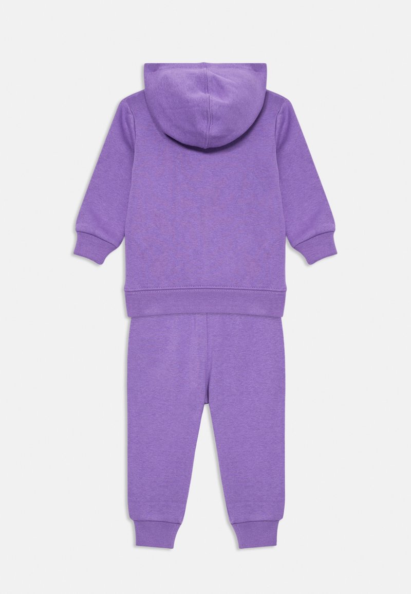Paarse hoodie en sweatpant-set gemaakt van zachte stof. Bevat ribgebreide boorden en een capuchon. Eenvoudig, sportief ontwerp zonder patronen of accenten.