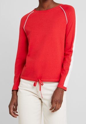 Red long-sleeve sweater with white side accents and drawstring hem. Soft, lightweight fabric with a crew neckline and raglan sleeves.