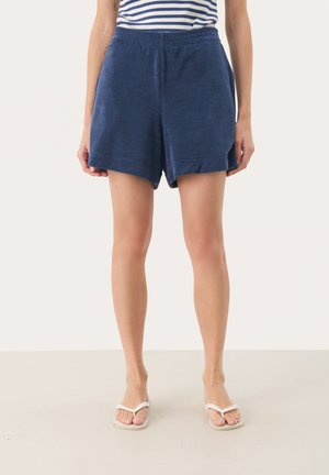Navy blue, soft terry cloth shorts with an elastic waistband, featuring a slightly loose fit and rolled hem. Worn with white flip-flops.