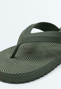 Tmavozelená gumová žabka s vlnitou textúrovanou podrážkou a širokým Y-tvarovaným remienkom na bežné nosenie.