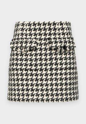 Μαύρη και λευκή φούστα με σχέδιο καρό σε υφή, διαθέτει δύο μπροστινές τσέπες με φθαρμένες άκρες και μαύρες λεπτομέρειες κουμπιού.