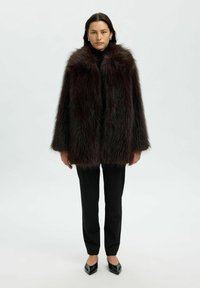 Faux bonten jas in donker bordeaux met een zachte textuur, met een open voorkant, brede mouwen, gecombineerd met zwarte broeken en puntige hakken.