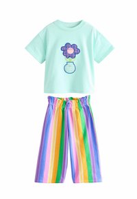 Haut vert menthe à manches courtes avec un motif floral rose et bleu, associé à un pantalon taille haute à jambes larges avec des rayures pastel verticales.