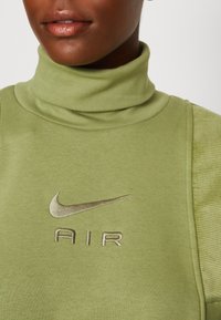 Ljusgrön sweatshirt med hög ribbad krage och broderad "AIR"-logotyp i beige, med en distinkt Nike-swoosh ovanför. Mjuk textur.