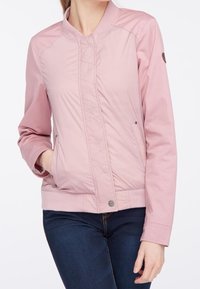 Veste bomber légère rose avec texture matelassée, poignets côtelés, col rond et poches latérales. Finition avec un patch logo sur la manche.