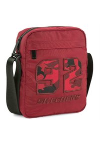 Bolso bandolera de tela roja con exterior acolchado, gran diseño en negro y camuflaje con el número "92", y correa ajustable negra.