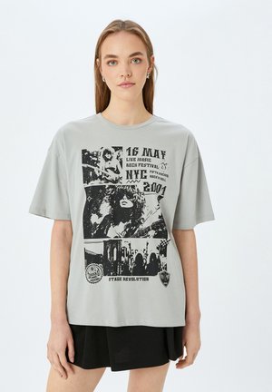 Grå bomulds t-shirt med korte ærmer, der viser et grafisk tryk af musikfestival scener og tekst, herunder datoer og steder i sort.