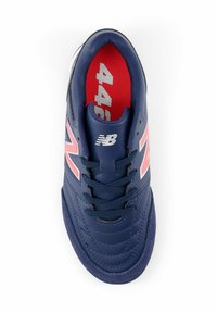 Tummansininen urheilujalkine, jossa on sileä synteettinen päällinen, vaaleanpunaiset korostukset, pyöreä varvas ja erottuva punainen pohjallinen. Varustettu vakiokengännauhoilla.