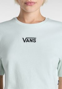 Lyse mintgrøn bomulds t-shirt med et sort broderet "VANS" logo på brystet og rund halsudskæring med korte ærmer.