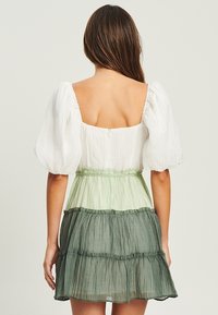 Vestido de mangas abullonadas con escote cuadrado, que presenta un degradado de blanco, verde claro y verde oscuro en capas, hecho de una tela ligera.