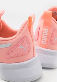 Scarpe sportive rosa con sopra in tessuto testurizzato, suola in gomma bianca, logo PUMA sul lato e linguette sul tallone e sulla linguetta.