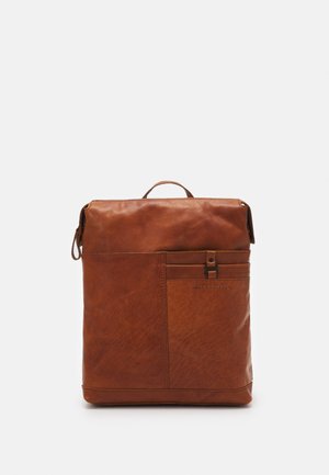 Sac à dos carré en cuir marron avec poche avant, poignée supérieure et détails de couture subtils sur un fond clair uni.
