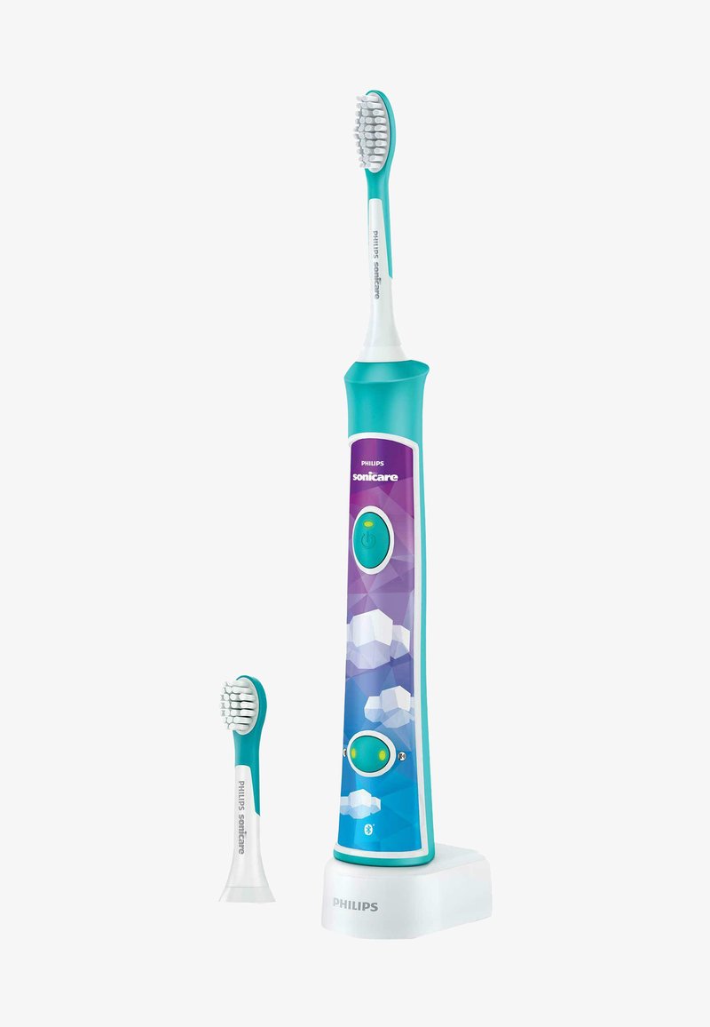 Elektrische Zahnbürste mit einem türkisfarbenen Griff, lila geometrischem Design, Ladebasis und einem kleineren Ersatzbürstenkopf daneben.