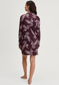 Dress da notte a maniche lunghe in tessuto bordeaux scuro con un motivo di gufo bianco, dal taglio morbido e con spacchi laterali per facilitare i movimenti.