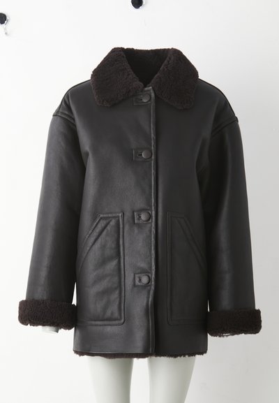 Crna kožna jakna s smeđim ovratnikom od ovčje kože, zatvaranjem na prednje kopče, dva bočna džepa i ukrasima od ovčje kože na manžetama.