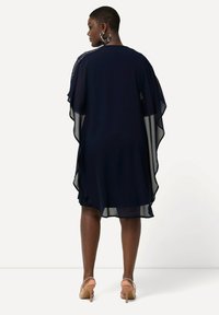 Abito in chiffon blu navy con maniche a mantella fluide, presenta un collo a barca e un leggero luccichio lungo la spalla. Design elegante e arioso.