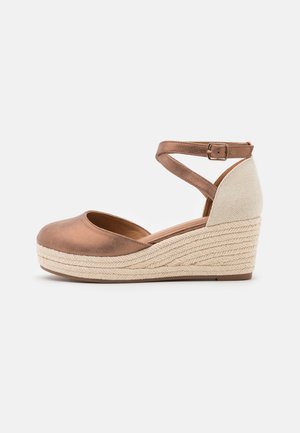 Sandale compensée en cuir marron avec un bout arrondi, une bride à la cheville et une semelle intermédiaire tressée imitation jute. Texture douce avec un accent de talon de ton clair.