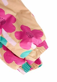 Tela con estampado floral en colores vivos como rosa, turquesa y beige; presenta puños elásticos y una textura satinada; detalle de superficie lisa visible.